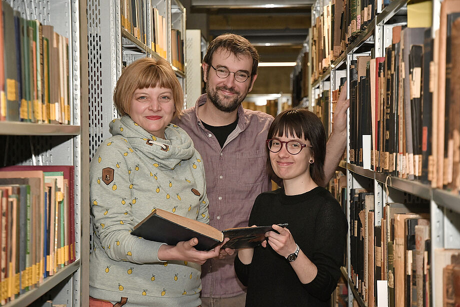 Nadine Kulbe, Robin Reschke und Elisabeth Geldmacher zwischen zwei Bücherregalen
