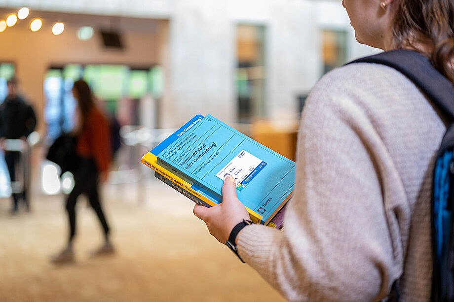 Woman with book and Campuscard in the SLUB