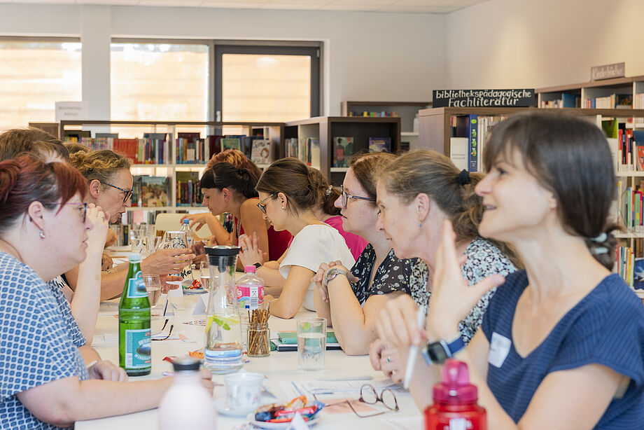 Zahlreiche Frauen tauschen sich an einem Tisch in der Landesfachstelle aus