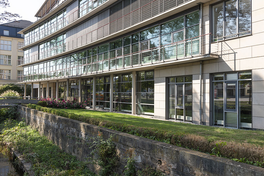 Großes Gebäude mit Glasfensterfront hinter Wassergraben