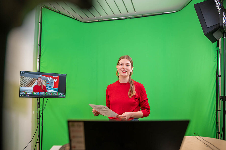 Frau spricht in Kamera vor grüner Wand im Greenscreen-Studio der SLUB